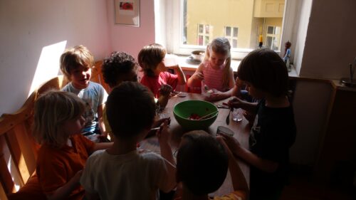 gruppe von kindern um einen küchentisch, erdbeeren essend