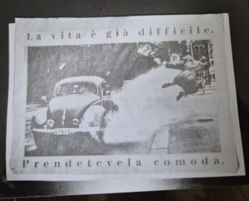 foto von zeitungsausriss mit einem alten käfer, der durch eine pfütze fährt und dabei einen menschen nassspritzt, der mit einem sprung ausweichen will.