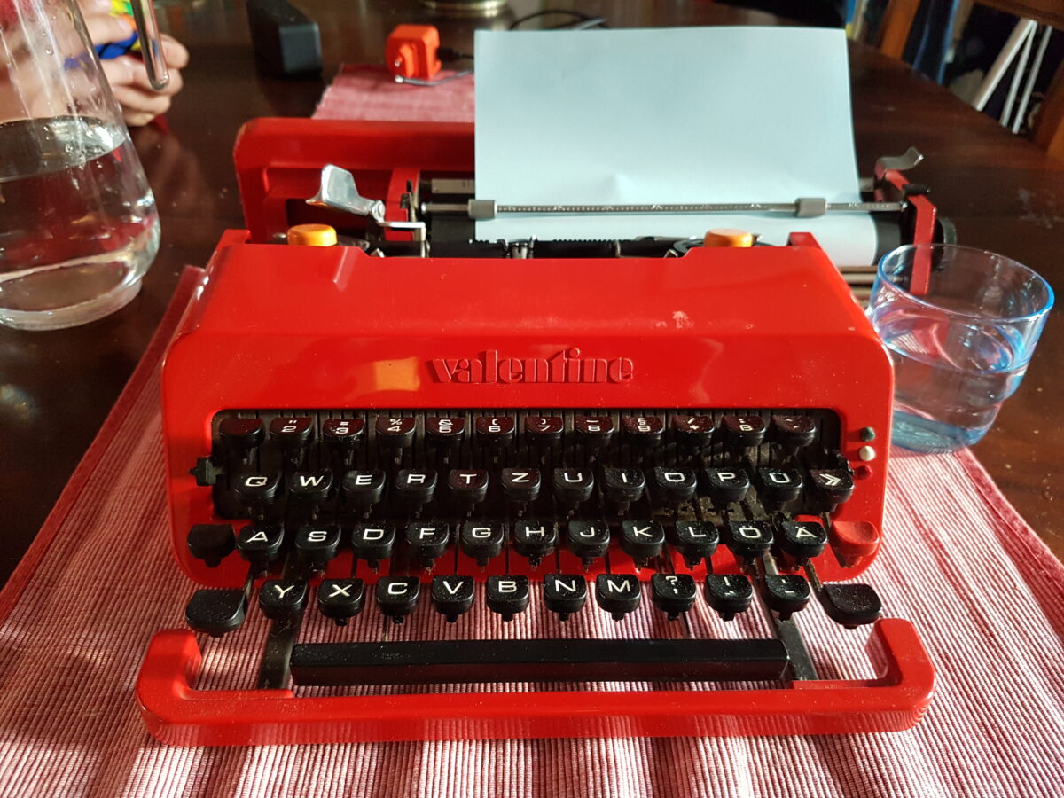 foto von einer roten mechanischen schreibmschine auf einem holztisch