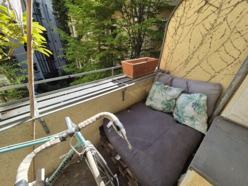Blick auf Balkon mit großem Kissen und kleineren Kissen auf einer Palette